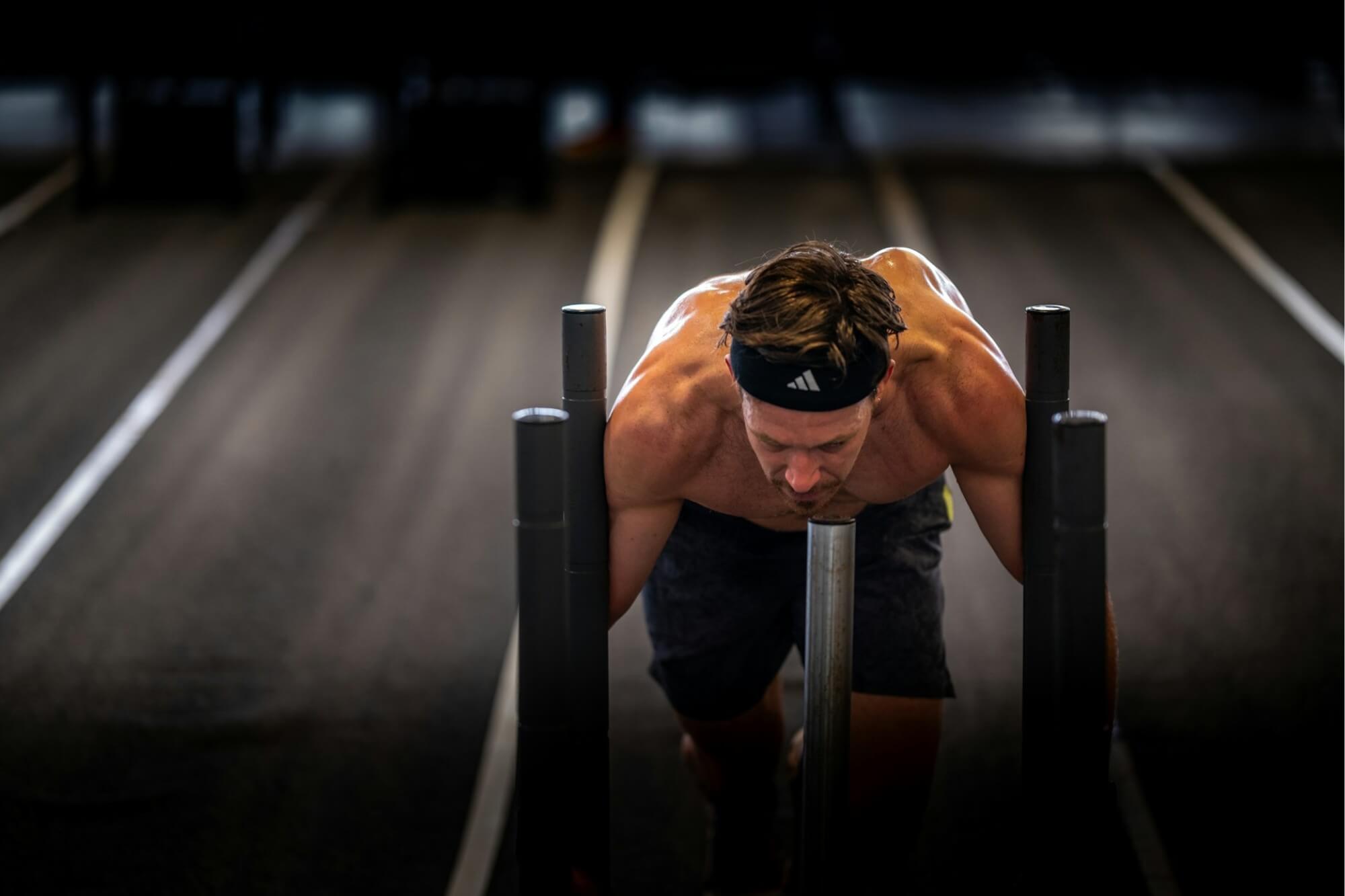 A man pushing a sled at a hyrox for a blog on the choosing the ultimate mens underwear for a hyrox race