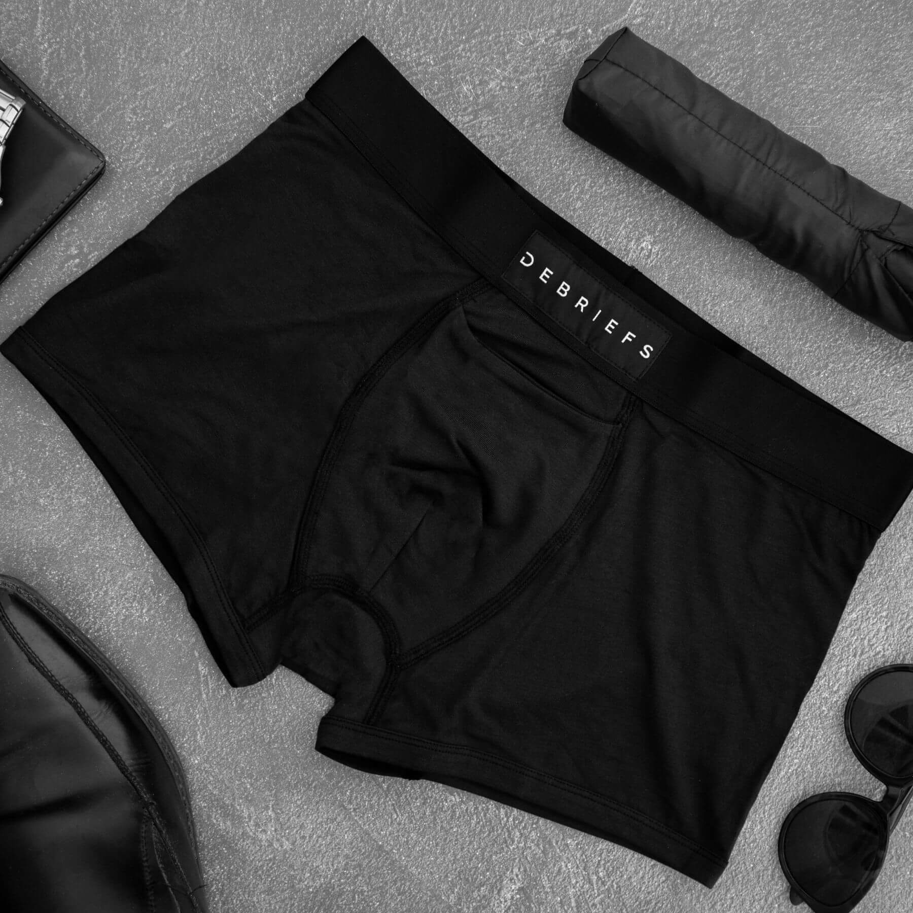 Pair of black Debriefs underwear laying on a table showcasing men's sustainable underwear. Mobile version
